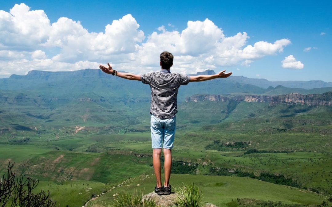 Financial Freedom experienced by a man with arms outstretched overlooking a beautiful valley.